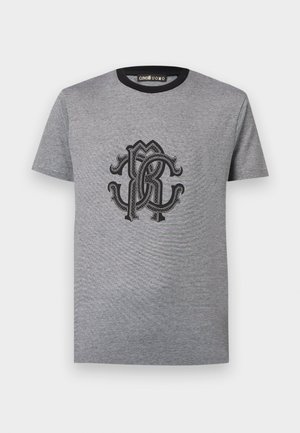 Siva kratka majica s crnim okruglim ovratnikom i ukrašenim crnim isprepletenim logotipom "CR" smještenim u sredini prsa.