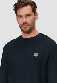 Marineblauw gebreid sweater met een ronde hals en een textuurontwerp. Bevat een klein merklabel op de borst en raglanmouwen.