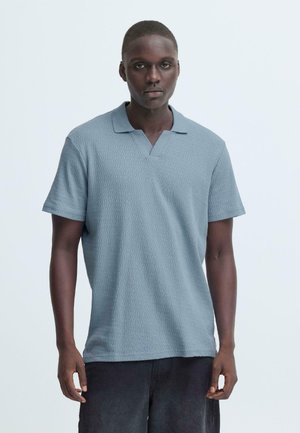 Hellblaues Poloshirt mit kurzen Ärmeln, V-Ausschnitt und strukturiertem Muster. Mit lockerer Passform, gefertigt aus weichem, atmungsaktivem Stoff.