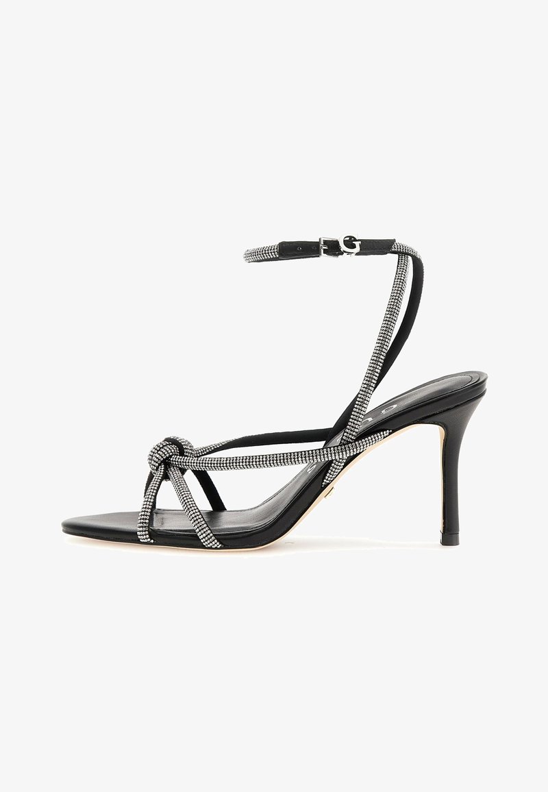 Fekete magassarkú szandál, amely csomózott elülső résszel, strasszokkal díszített pántokkal és vékony stiletto sarokkal rendelkezik. Sima textúra.