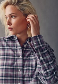 Purple and gray plaid button-up shirt with a collar and white buttons. Features long sleeves and a soft fabric texture.