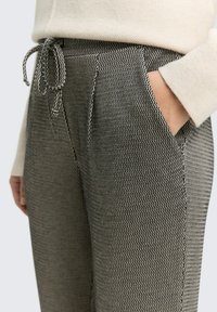 Gestructureerde grijs en zwarte gestreepte broek met een elastische tailleband en drawstring, uitgerust met zijzakken en een getailleerde pasvorm.