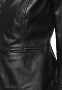 Svart läderjacka med en slät textur, skräddarsydd passform och diagonala sömmar. Inkluderar dragkedjestängning och sidfickor.