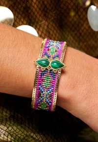 Bracelet en perles présentant des motifs éclatants de rose, bleu et vert, encadré de métal doré et rehaussé de deux pierres vertes en forme de goutte.