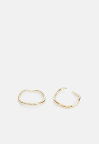 Pendientes de metal en tono dorado con un diseño suave y curvado. Uno tiene forma de corazón y el otro presenta una forma circular abierta.