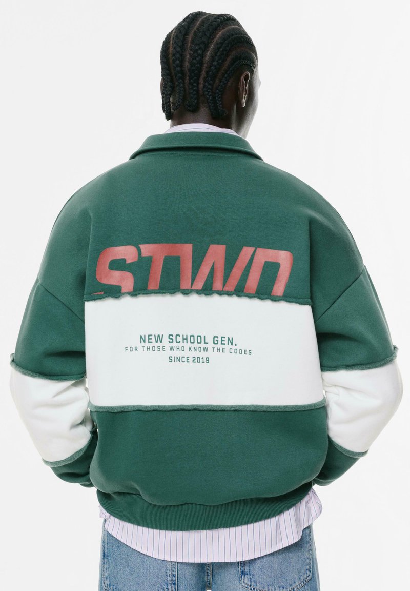 Giacca a blocchi di colore verde e bianco con una finitura testurizzata, caratterizzata da lettering e dettagli rossi audaci sulla schiena.