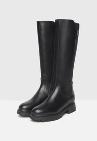 Bottes noires en cuir hauteur genou avec une texture lisse, bout rond et semelle crantée. Présente une fermeture éclair sur le côté et un détail de couture minimal.