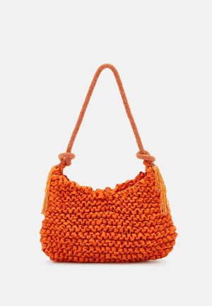 Orange knitted handbag with thick braided strap and tassels on a plain white background.