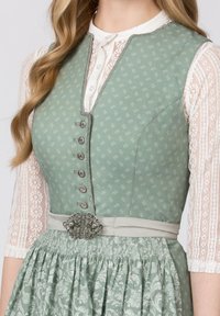 Traditionelles grünes Dirndl mit Blumenmuster, Spitzenärmeln, silbernen Knöpfen und einem dekorativen Taillengürtel mit einer kunstvollen Metallschließe.