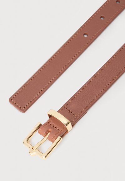 Καφέ δερμάτινη ζώνη με χρυσή μεταλλική αγκράφα και ραμμένα άκρα, τοποθετημένη επίπεδα σε φωτεινή επιφάνεια.