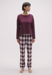 Μπορντό μακρυμάνικη μπλούζα σε συνδυασμό με γκρι και μπορντό καρό πιτζάμα παντελόνια. Μαλακό ύφασμα, χαλαρή γραμμή και ελαστικές μανσέτες στους αστραγάλους.