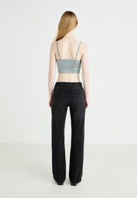Pantaloni in denim neri con una vestibilità a gamba dritta, abbinati a un top corto di colore blu argento con schiena arricciata e spalline sottili.
