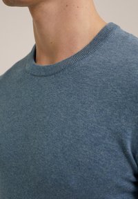 Light blue short-sleeve sweater with a round neckline. The fabric appears soft with a smooth texture and subtle knit pattern.