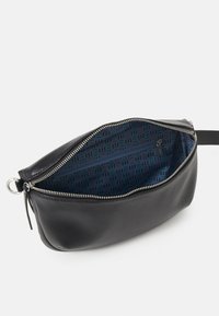 Czarna skórzana torba o gładkiej fakturze, z zamknięciem na zamek i wzorzystym granatowym wnętrzem z geometrycznymi wzorami.