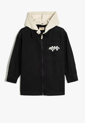 Zwarte denimjas met een grijze capuchon, voorzien van een rits aan de voorkant en een borstzak met "NIEUWE DOELEN" in witte letters.