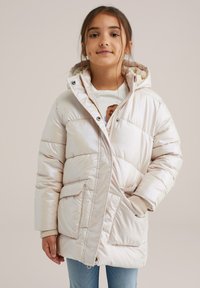 Ljust beige pufferjacka med foder i päls, tryckknappar, stora framfickor, ribbade muddar och kviltad textur.