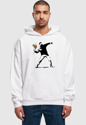 White hoodie featuring a black stencil-style artwork of a figure throwing a bouquet of flowers. Fabric appears soft with a front pocket.