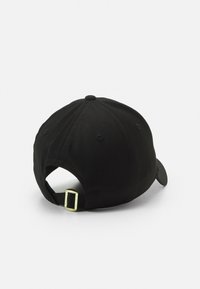 Gorra de béisbol negra con tejido texturizado, visera curvada y un regulador de metal dorado en la correa en la parte trasera.