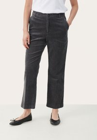 Pantalon en velours côtelé gris à coupe droite, avec une fermeture à boutons, des poches latérales et une texture côtelée subtile. Porté avec des ballerines noires.