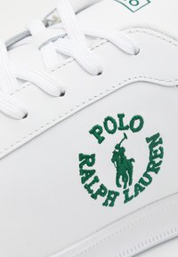 Vita sneakers i texturerat läder, med grön broderad "POLO RALPH LAUREN"-logotyp och en polo-spelare; vita snören ingår.