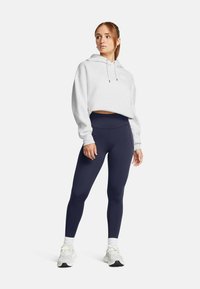 Utvärdade vita hoodien med dragsko, som kombineras med högmidjade marinblå leggings och vita sportskor. Slät, mjuk tyg.