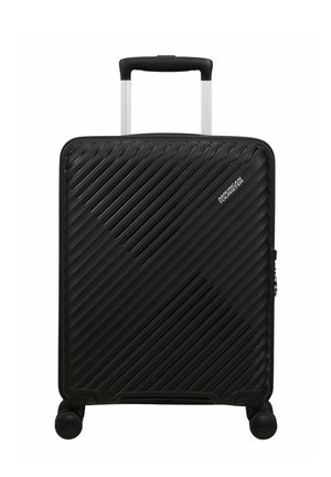 Valigia rigida nera con linee strutturate diagonali, quattro ruote, manico telescopico e logo "American Tourister" sul davanti.