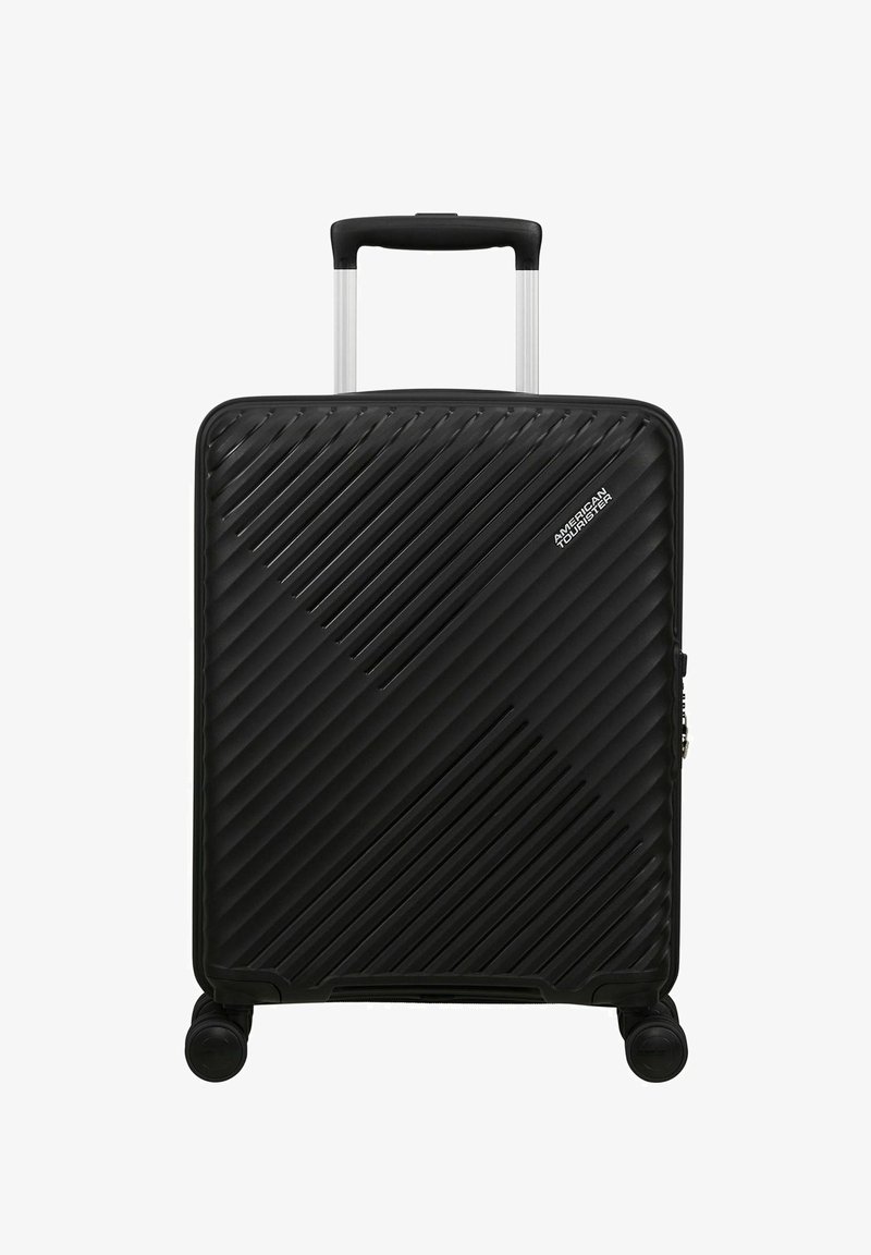 Valise rigide noire avec des lignes texturées diagonales, quatre roues, poignée télescopique et logo « American Tourister » sur le devant.