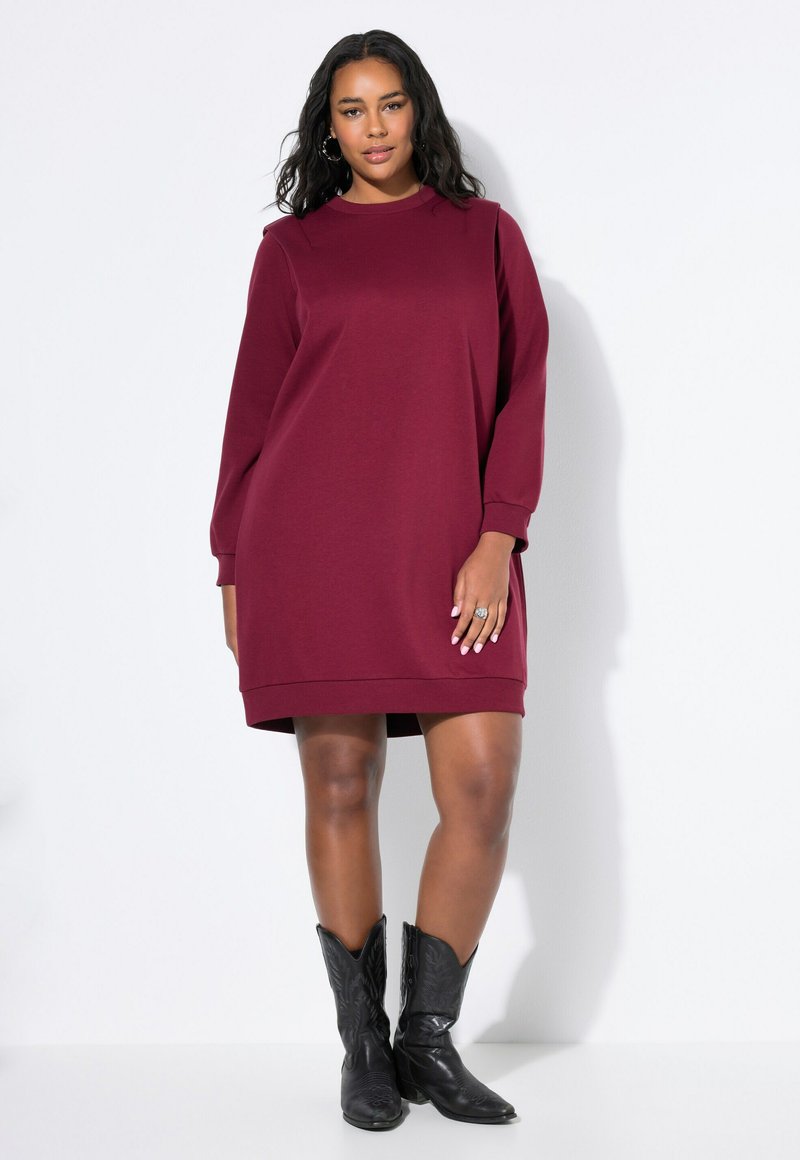 Vestido sudadera burdeos de Marlyn con mangas largas, cuello acanalado y dobladillo, combinado con botas de vaquero negras. Textura de tela suave.