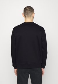 Felpa nera con scollo rotondo, polsini e orlo a coste, vestibilità classica, realizzata in morbido tessuto misto cotone. Texture liscia e opaca.