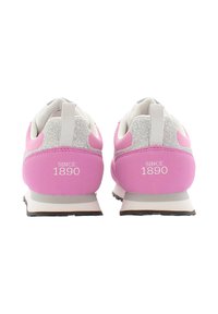 Růžové sportovní boty s bílými a třpytivými akcenty, vybavené polstrovaným límcem a patou, s nápisem "SINCE 1890" vytištěným na zadní straně.