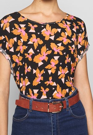 Zwart shirt met oranje en roze abstract bloemmotief, gedragen met een blauwe spijkerbroek en een bruine tekstuurriem met een gouden gesp.