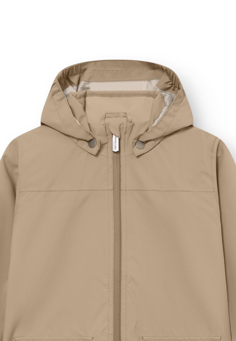 Giacca impermeabile beige con cappuccio, zip frontale e bottoni a pressione. Texture liscia e design minimalista senza pattern visibili.