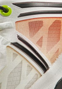 Scarpa sportiva con tomaia in rete e sovrapposizioni che sfumano dall'arancione al bianco, dettagli testurizzati e particolari neri. Sistema di allacciatura distintivo.