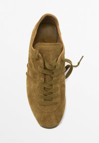 Baskets en daim marron avec bout arrondi, lacets plats et intérieur lisse. Présente une couture minimale et une semelle texturée.