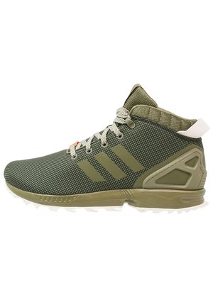 Scarpa da ginnastica alta verde con tessuto strutturato, tre strisce sul lato, lacci bianchi e verdi e suola robusta per uso esterno.