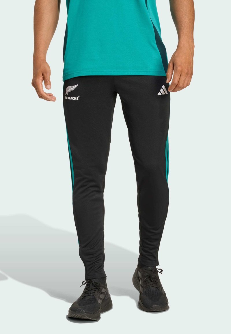 Zwarte sportbroek met turquoise zijsstripes, gemaakt van glad materiaal. Heeft een logo op de linkerdij en een aansluitend ontwerp.
