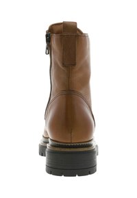 Bottine en cuir marron avec une fermeture éclair sur le côté, un bout rond et une semelle en caoutchouc noir texturé avec des détails de couture sur les côtés.
