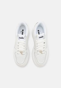 Sneakers bianche con dettagli perforati, esterno in pelle sintetica, lacci piatti, linguetta imbottita e loghi discreti sulla linguetta e sui lati.