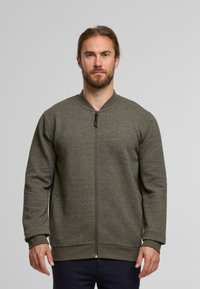 Bomberjakke i struktureret olivengrønt stof med lynlås foran, rund udskæring, ribbede manchetter og kant.