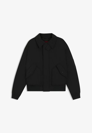 Black bomber jacket with a collared neck, snap button closure, and two front flap pockets. Features ribbed cuffs and hem. Textured fabric.