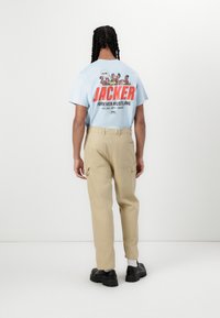 Light blue t-shirt with graphic print on the back, paired with beige cargo pants and black chunky shoes.