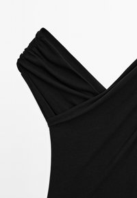 Sort cropped top med V-hals design. Har samlet stof på skuldrene og en glat, blød tekstur.