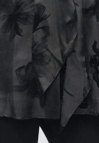Čierna priesvitná látka s kvetinovými vzormi, s závesným dizajnom a nerovným lemom. Textúra je hladká, čo dodáva ľahkosť.