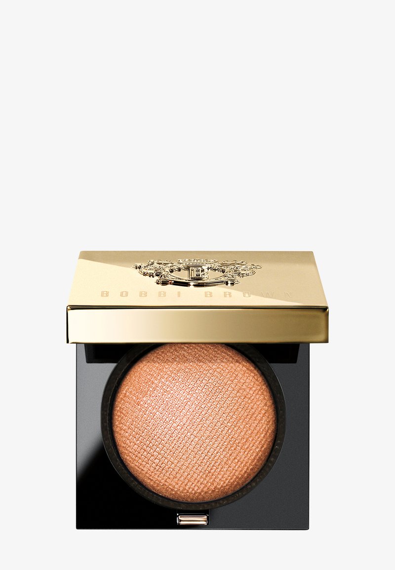 Bobbi Brown poeder in een vierkante zwarte compact met een gouden deksel, met een gestructureerd perzikkleurig product erin, en een geperst ontwerp bovenop.