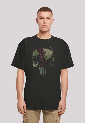 Black cotton t-shirt featuring a colorful graphic of a skull surrounded by splatters in green and red shades. Loose fit with short sleeves.
