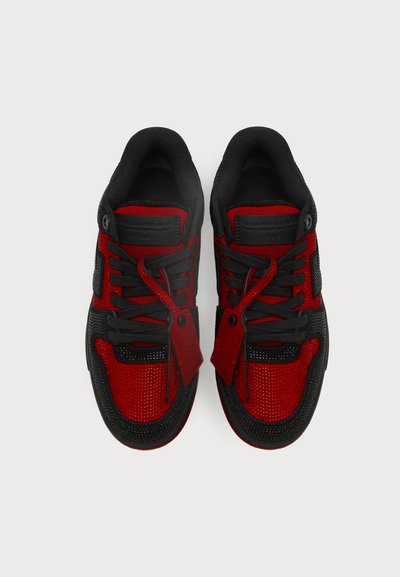 Paire de chaussures de sport rouges et noires avec lacets et étiquettes, vues de dessus sur un fond clair uni.