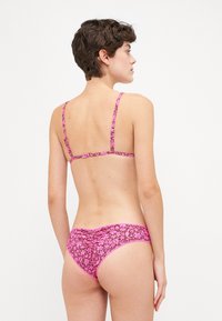 Biquíni padrão floral em tons de rosa com alças finas, apresentando um design de costas franzidas e textura suave, adequado para uso em natação.
