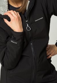Schwarze isolierte Jacke mit Reißverschluss, Fleecefutter, verstellbaren Bündchen und Logo-Akzenten auf der Brust und dem Ärmel.