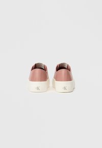Pink synthetic leather sneakers with white rubber soles, rounded toe, and subtle branding on the heel. Smooth texture with cushioned ankle support.