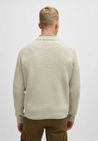 Maglione a maglia color beige chiaro con un motivo testurizzato a nido d'ape, polsini e orlo a coste; presenta una vestibilità comoda e un colletto alto.